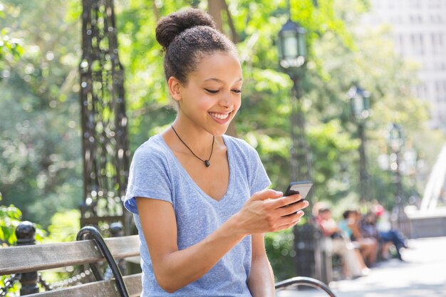 Belle métisse jeune femme taper sur un téléphone mobile