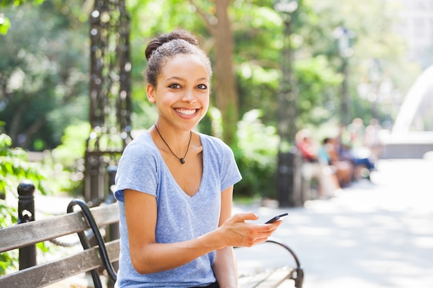 Belle métisse jeune femme taper sur un téléphone mobile