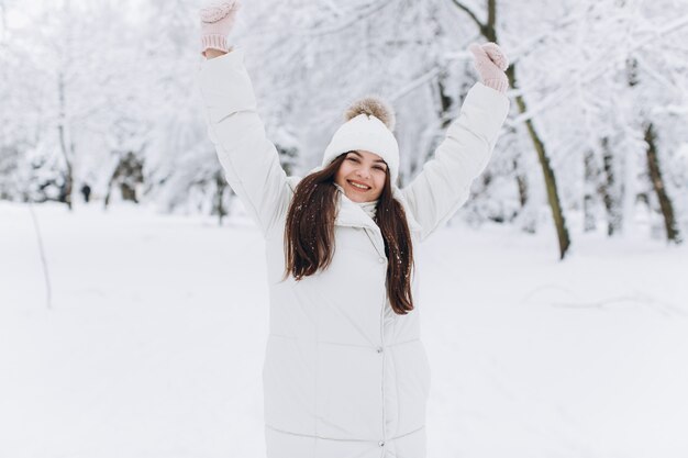 Une belle et mode femme en vêtements chauds blancs marchant dans un temps neigeux.