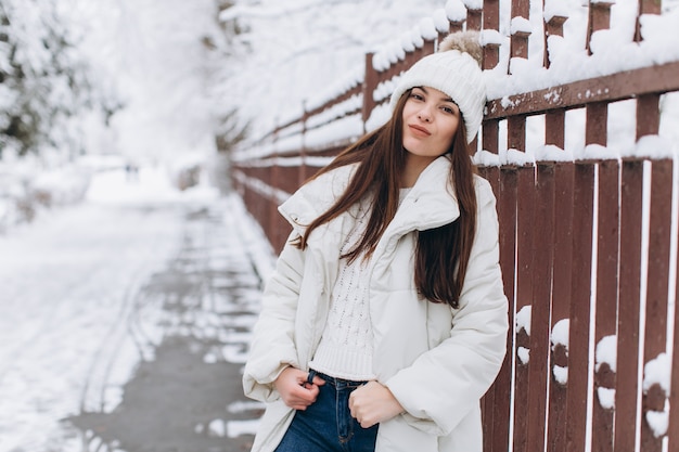 Une belle et mode femme en vêtements chauds blancs marchant dans un temps neigeux.