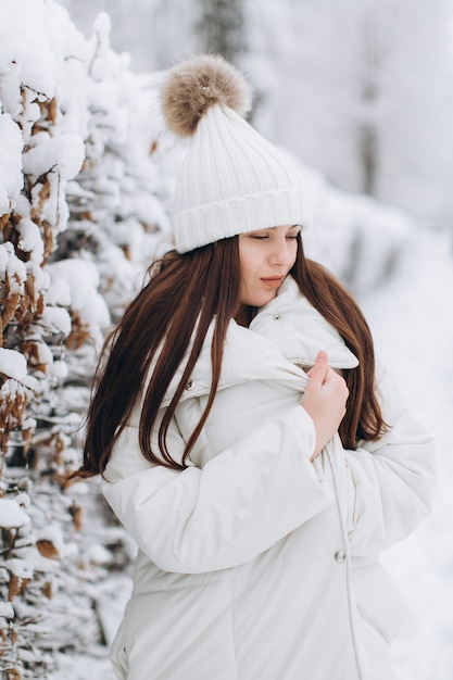 Une belle et mode femme en vêtements chauds blancs marchant dans un temps neigeux.