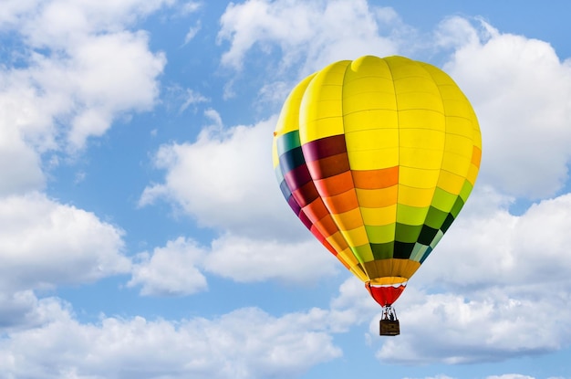 Belle montgolfière colorée survolant un ciel bleu avec des nuages blancs sport et aventure