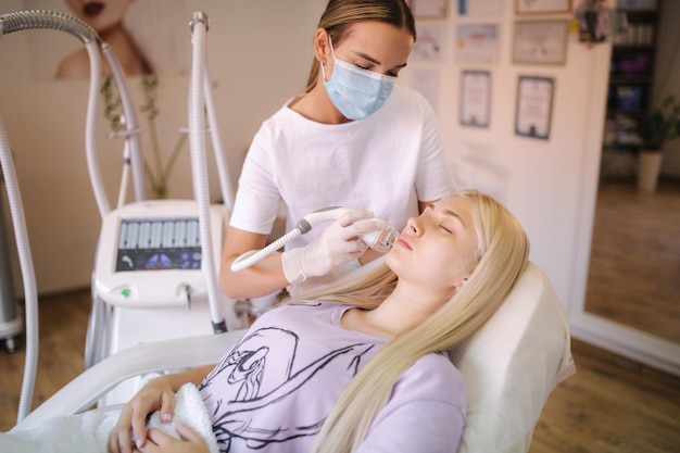 Belle patiente reçoit un traitement de la peau du visage en position couchée à la clinique médicale