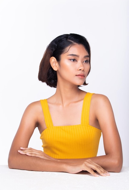 Belle peau bronzée femme porter une robe jaune épaule ouverte avec un look propre maquillage et cheveux bouclés Portrait jeune fille à la mode naturelle attrayante visage express sentir sourire isolé fond blanc