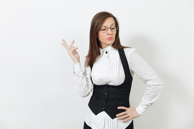 Belle pensive intelligente caucasienne réfléchie jeune femme d'affaires aux cheveux bruns en costume noir, chemise blanche et lunettes isolées sur mur blanc