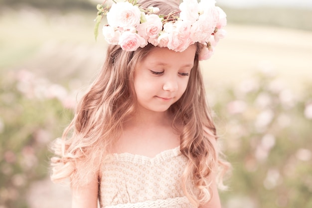 Belle petite fille de 4 à 5 ans portant une couronne de fleurs à l'extérieur. Enfant élégant.