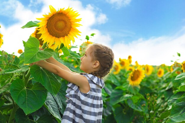 Belle petite fille appréciant la nature Heureuse enfant de sexe féminin souriant debout dans le champ de tournesols