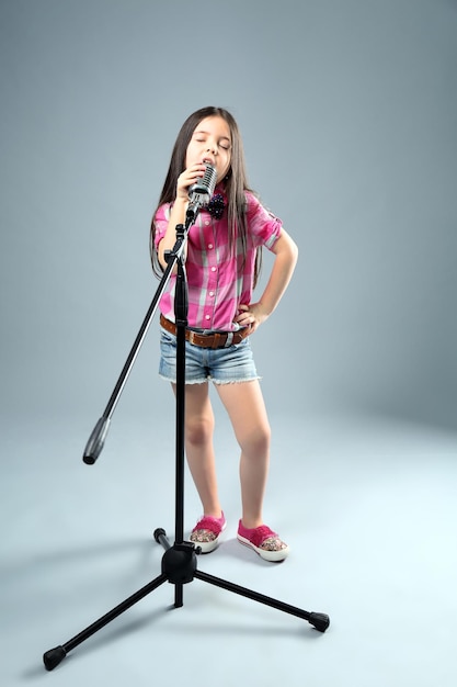 Belle petite fille artistique avec microphone sur fond gris