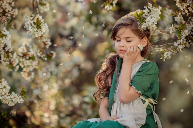 Belle petite fille assise dans un jardin fleuri