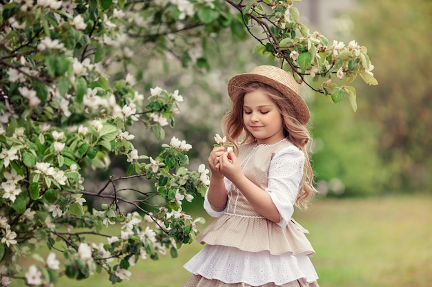 Belle petite fille assise dans un jardin fleuri