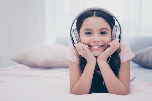 Belle petite fille assise sur son lit avec un casque