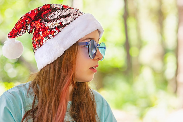 Belle petite fille aux cheveux longs portant un chapeau de père Noël. Fille à Noël