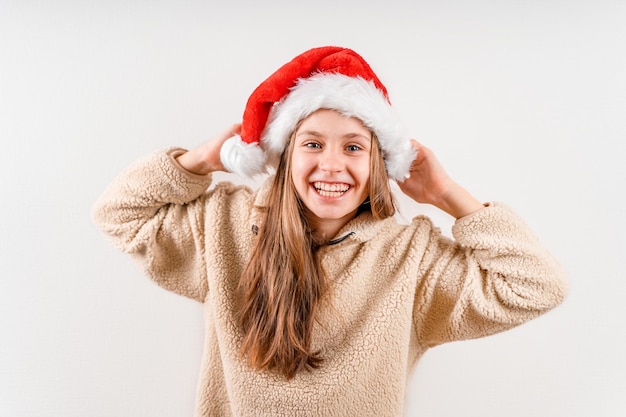 Une belle petite fille blonde dans un chapeau de Noël rouge sourit