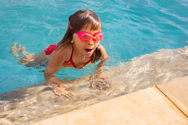 Belle petite fille caucasienne dans la piscine rafraîchissante en été