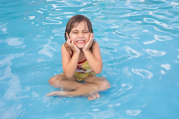 Belle petite fille caucasienne dans la piscine rafraîchissante en été