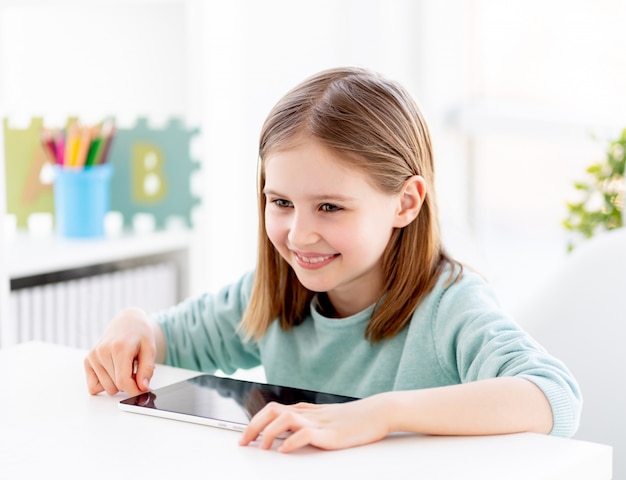 Belle petite fille à côté de la tablette