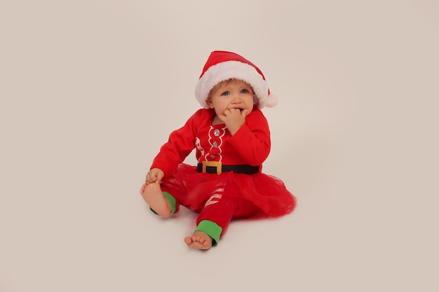 belle petite fille dans un costume de Noël et bonnet de noel sur fond blanc