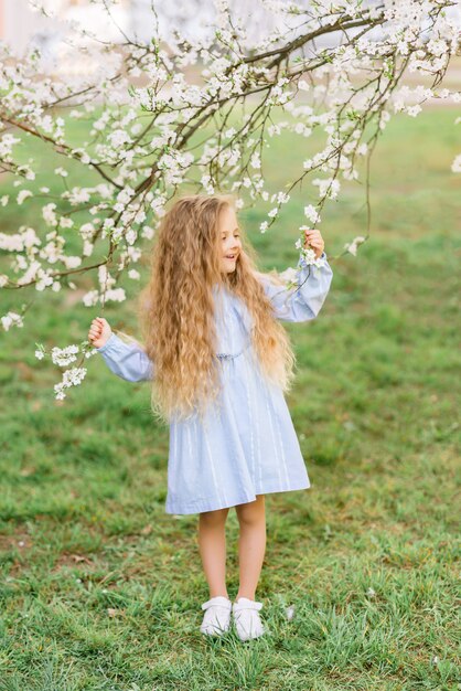 Belle petite fille dans un jardin fleuri. Photo de printemps