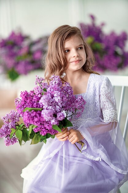 Belle petite fille dans une robe délicate avec des fleurs de lilas
