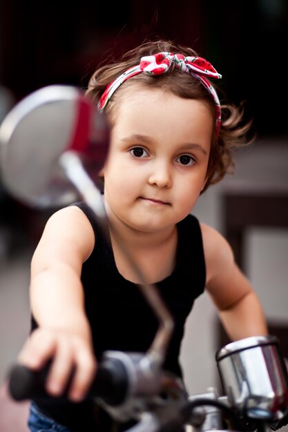 Photo belle petite fille dans un style motard sur une moto.