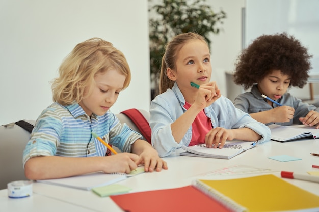 Belle Petite Fille Détournant Les Yeux Tout En écoutant Les Enfants Des Enseignants étudier Et Prendre Des Notes