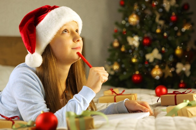 Photo belle petite fille écrivant une lettre au père noël à l'intérieur de noël