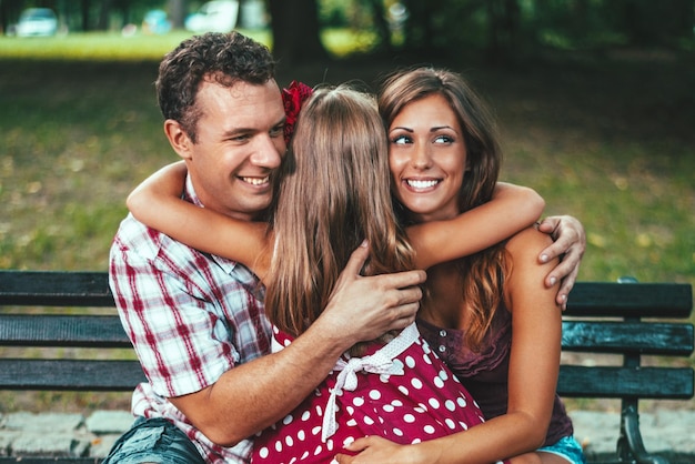 Belle petite fille a embrassé ses parents dans le parc.