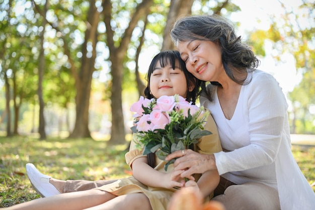 Belle petite-fille et grand-mère asiatique tenant un beau bouquet relaxant dans le parc