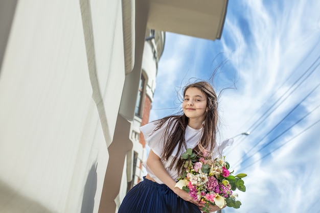 Belle petite fille heureuse avec des bouquets de fleurs se promenant dans la ville