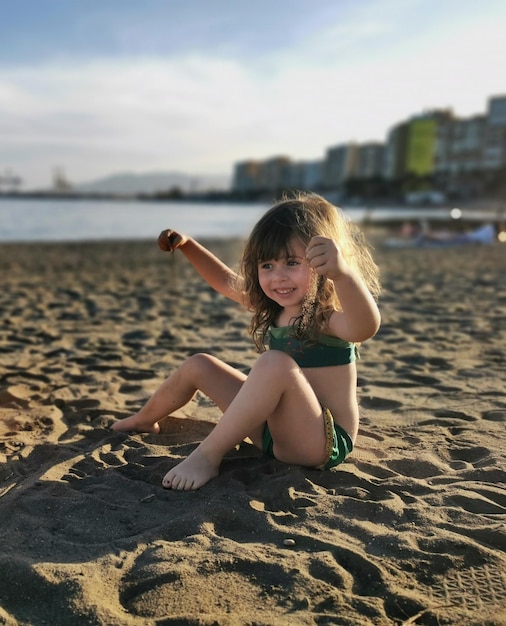 Belle petite fille jouant avec du sable sur la plage