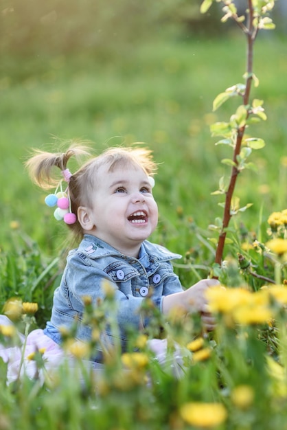 Une belle petite fille jouant avec un jeune arbre dans un jardin d'été