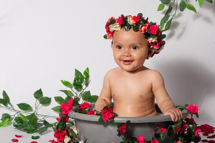Photo belle petite fille latine de 9 mois assise sur un seau à l'air très heureuse