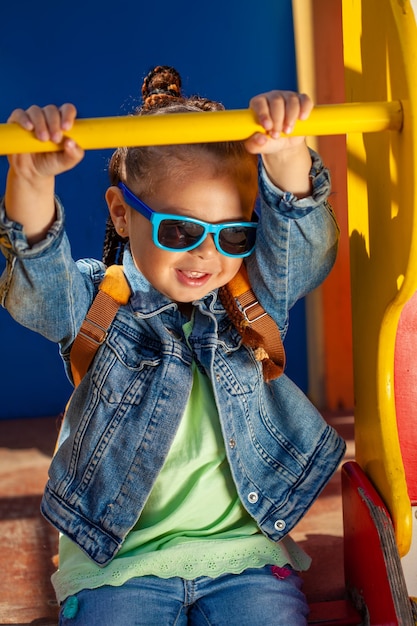 Photo belle petite fille à lunettes de soleil avec des nattes dans le parc