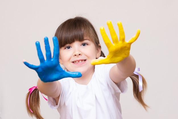 Belle petite fille avec les mains dans la peinture