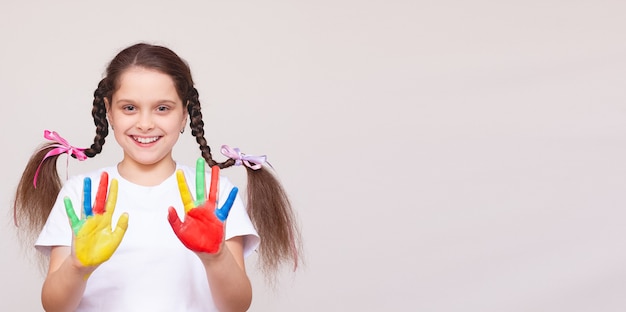 Belle petite fille avec les mains dans la peinture