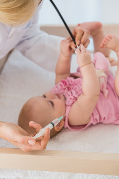 Belle petite fille et médecin en utilisant une seringue et une aiguille