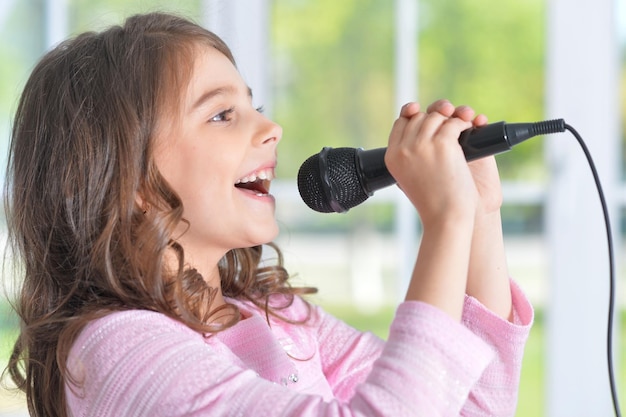 Belle petite fille avec microphone à la maison