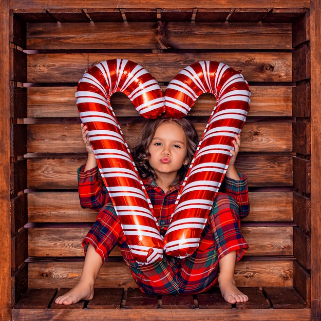 Belle petite fille mignonne dans un endroit carré en bois dans les décorations de Noël