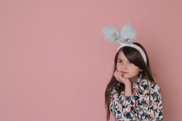 Belle petite fille avec des oreilles de lapin tenant des fleurs