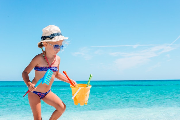 Belle petite fille à la plage s'amuser avec des outils de sable