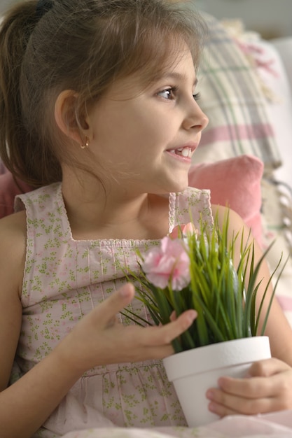 Belle petite fille posant avec des fleurs à la maison.