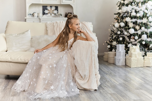 Belle petite fille en robe de fête à l'intérieur de Noël