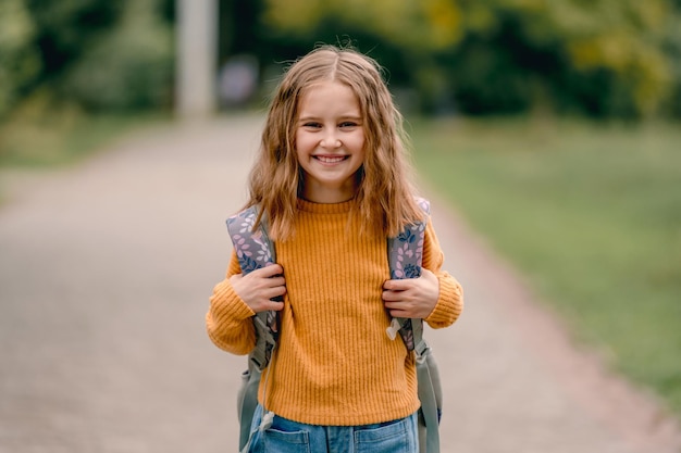 Belle petite fille avec sac à dos après l'école en souriant et en regardant la caméra. Portrait d'une enfant préadolescente à l'extérieur à l'automne