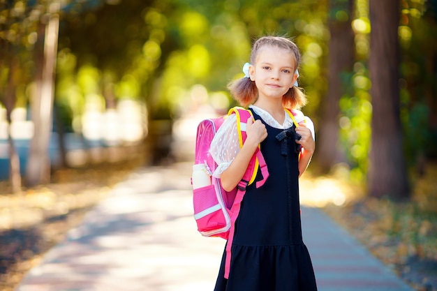 Belle petite fille avec sac à dos marchant dans le parc prêt à rentrer à l'école, tomber à l'extérieur, concept de l'éducation.