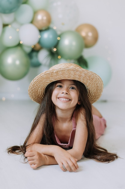 Belle petite fille souriante à la peau foncée aux yeux marrons et aux cheveux noirs dans un chapeau de paille