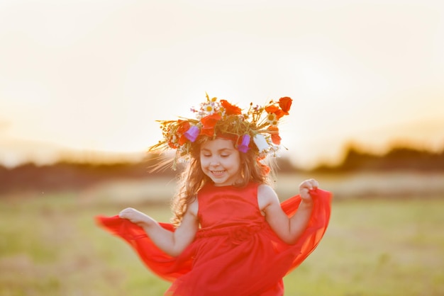 Belle petite fille souriante vêtue d'une robe rouge tourne avec une couronne sur la tête