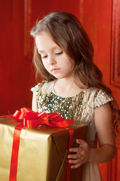 Belle petite fille tenant une boîte-cadeau de Noël. Concept de célébration de Noël et du nouvel an. Vacances d'hiver.