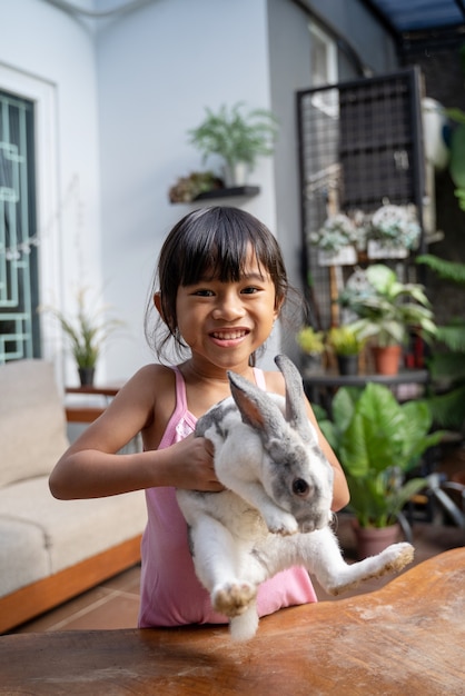 Belle petite fille tenant un lapin drôle en jouant à la maison