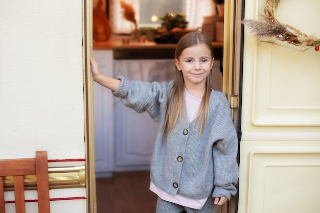 belle petite fille en vêtements décontractés debout près de la porte de la remorque sur le porche RV house in garden