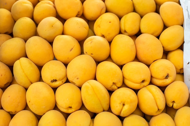 Belle photo avec beaucoup de gros abricots jaunes frais vendus sur le marché.